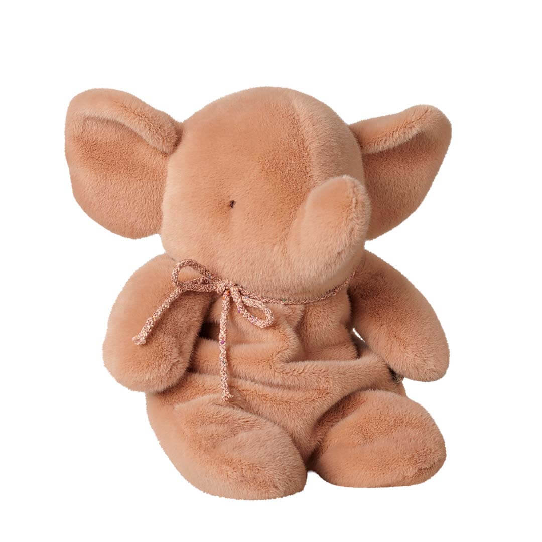 A plush elephant toy in a warm peachy-brown color, sitting upright and wearing a matching fabric bow around its neck, isolated on a white background.