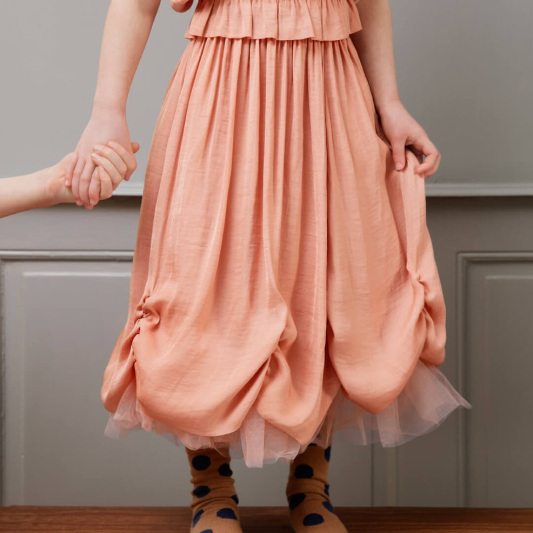 Person wearing a peach dress with a plain background