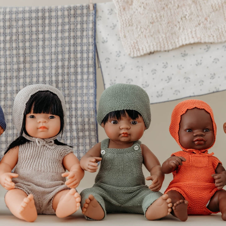 Three dolls with different hair colors and outfits sitting together.
