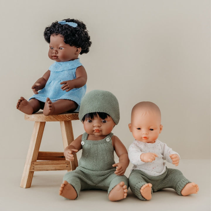 Three dolls in various outfits on a neutral background