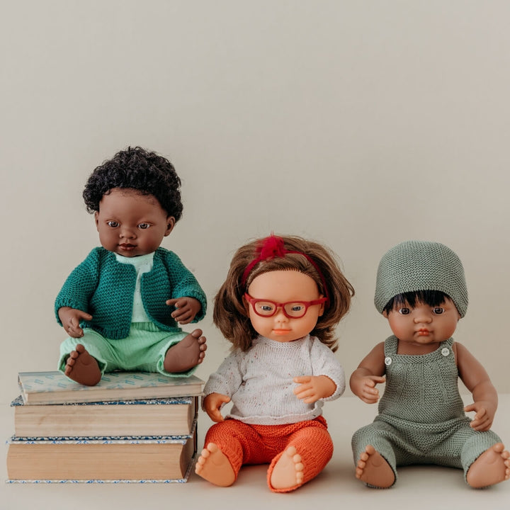 Three minland realistic dolls with different outfits and accessories on a neutral background
