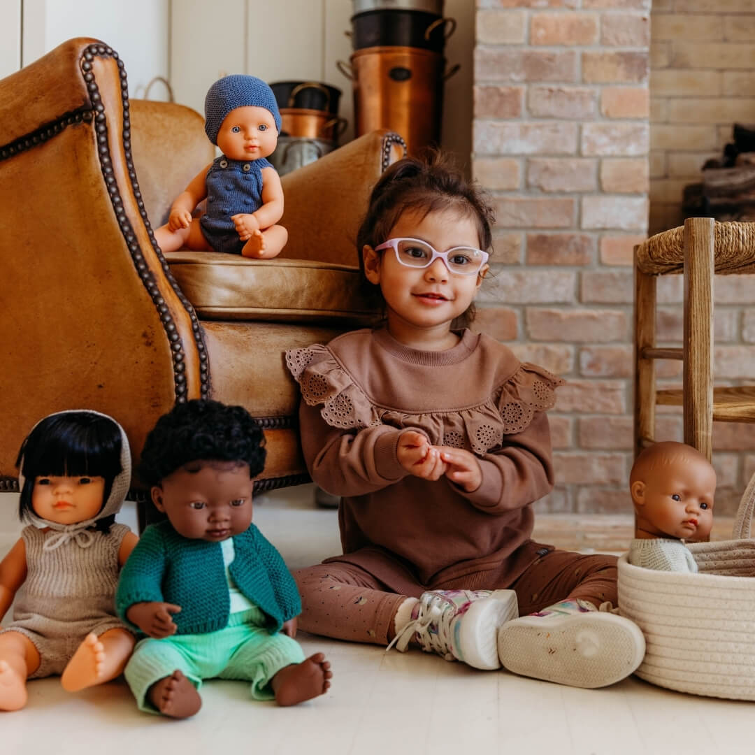 Child sitting on the floor with dolls in a home setting