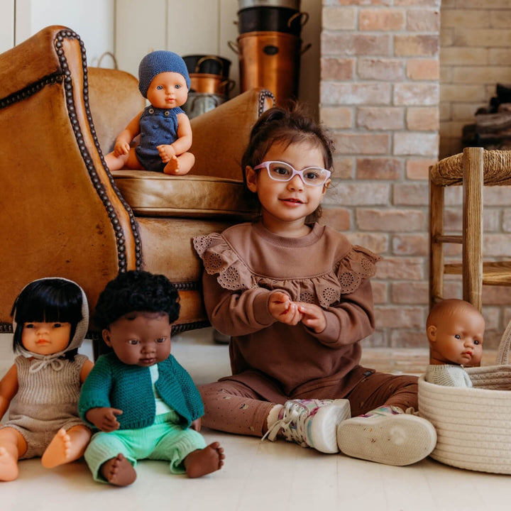Child sitting on the floor with dolls in a home setting