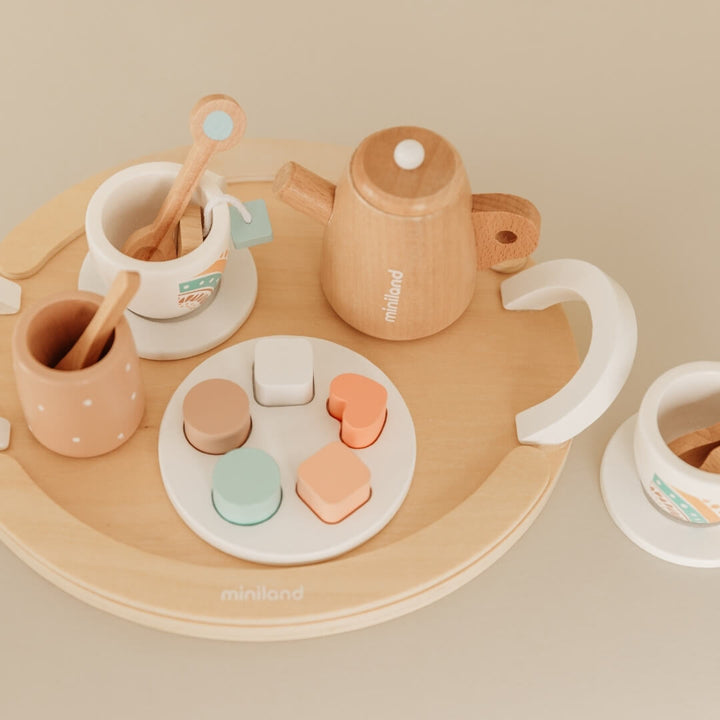 Wooden toy tea set with cups, saucers, and a tray on a beige background