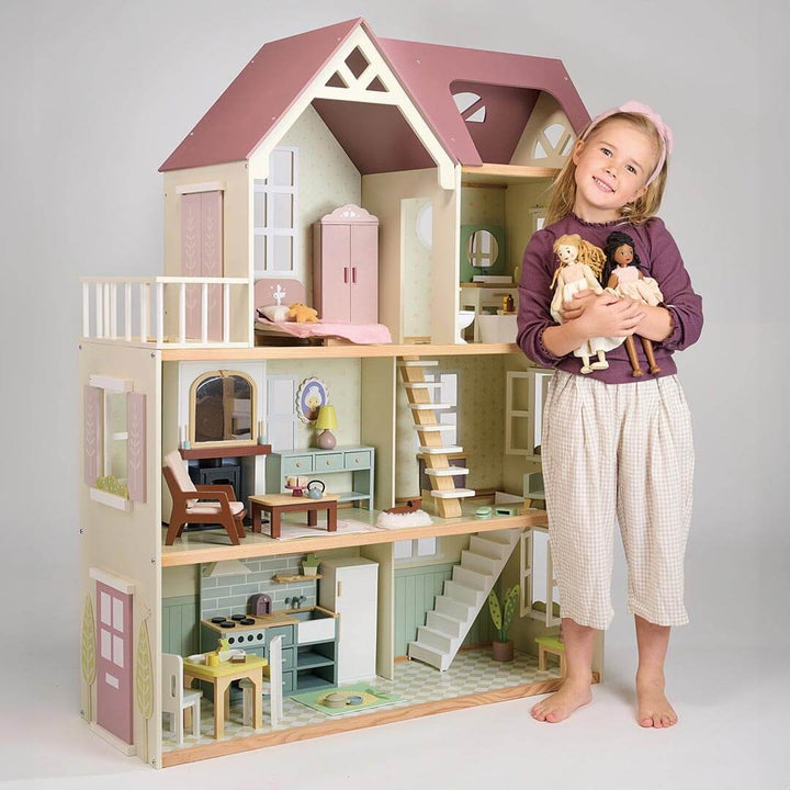 Child standing in front of Tender Leaf Toys Mulberry Mansion Wooden Dollhouse with 2 dolls