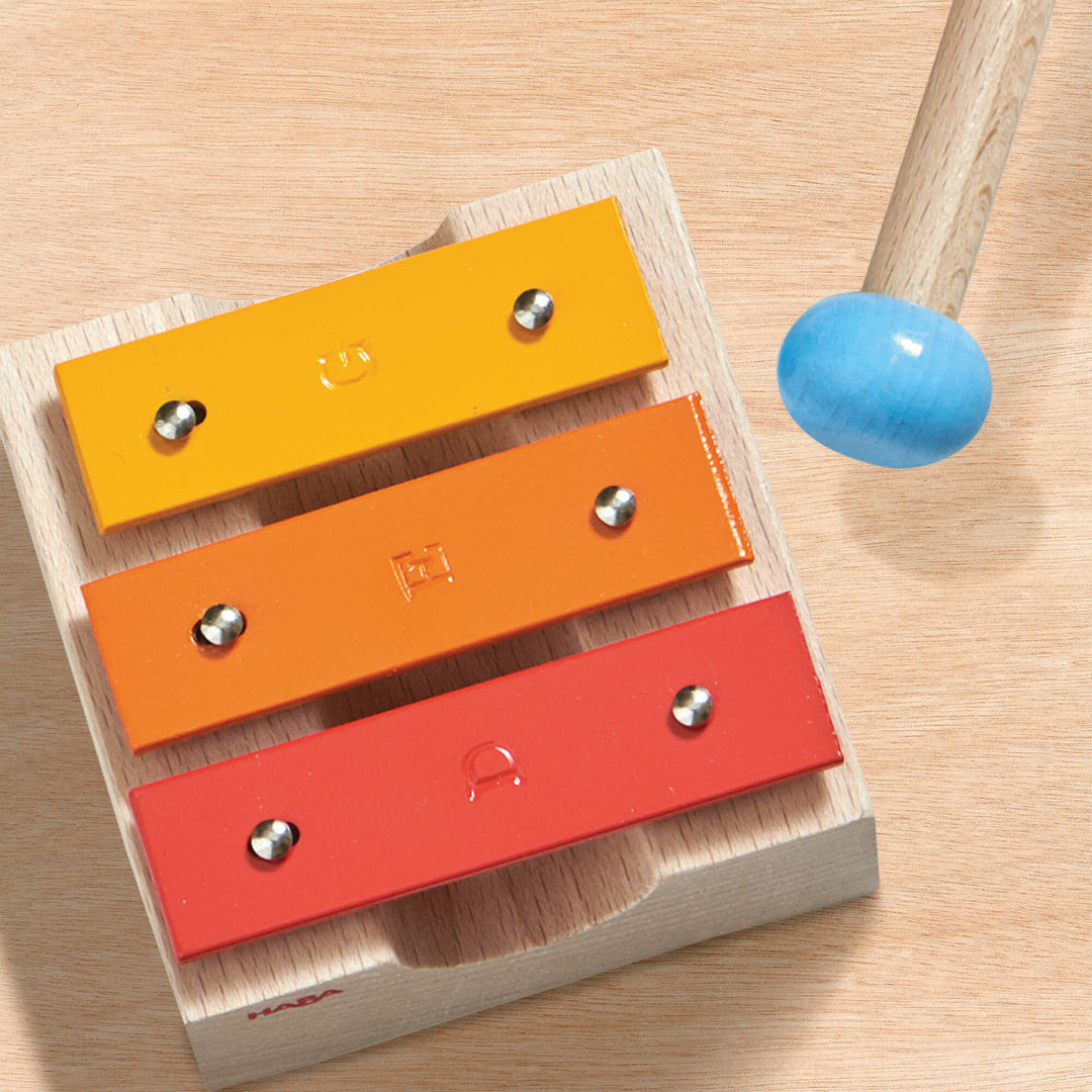 Metallophone and mallet on wooden background