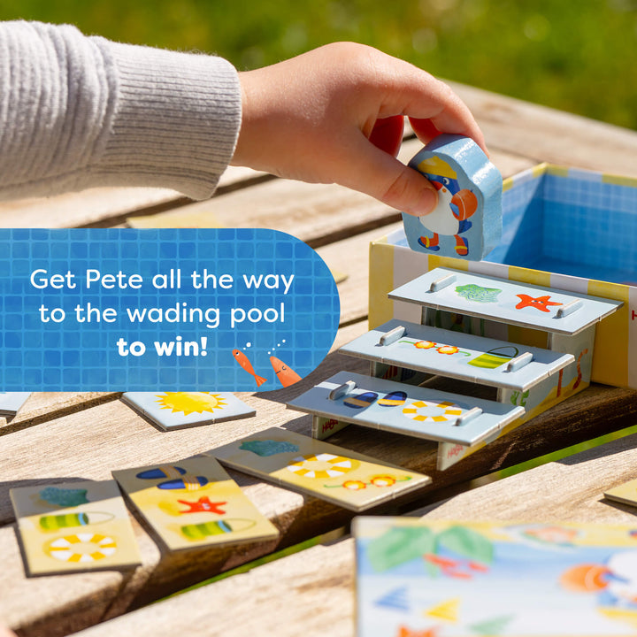 Child playing with a HABA board game on a wooden surface outdoors