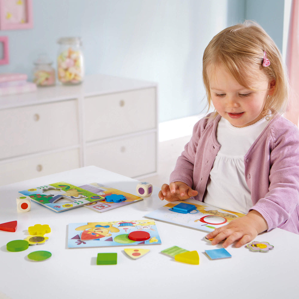 A young child playing with colorful shape puzzles at a white table.