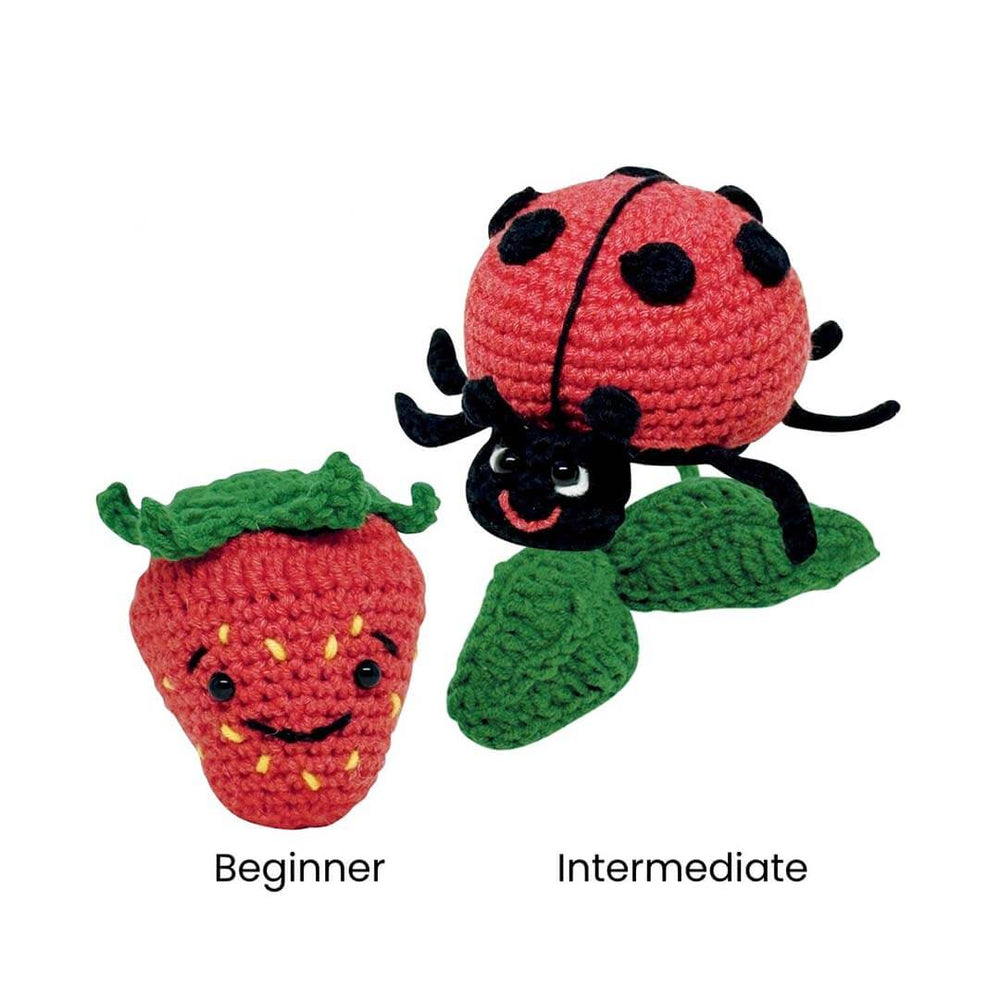 Two crocheted plush toy animals on a white background: a red strawberry with green leaves labeled 'Beginner' and a red ladybug with green leaves labeled 'Intermediate'.