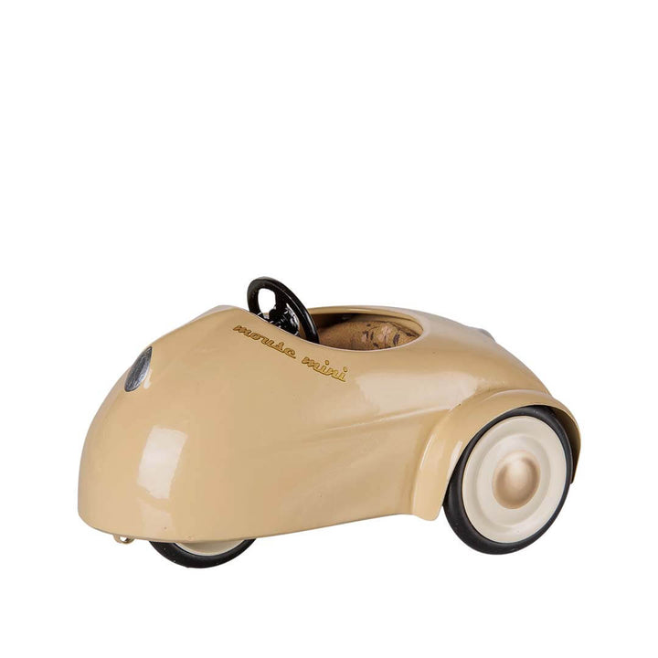 A vintage-style beige pedal toy car with black wheels and a black steering wheel,  shown against a plain white background.