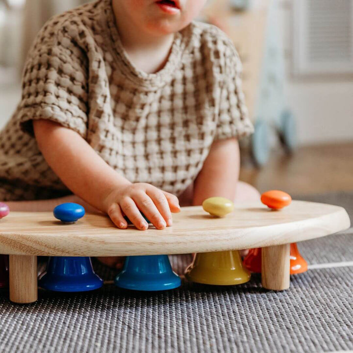 A child's hand resting on the Pentatonic Pat Bell Station.