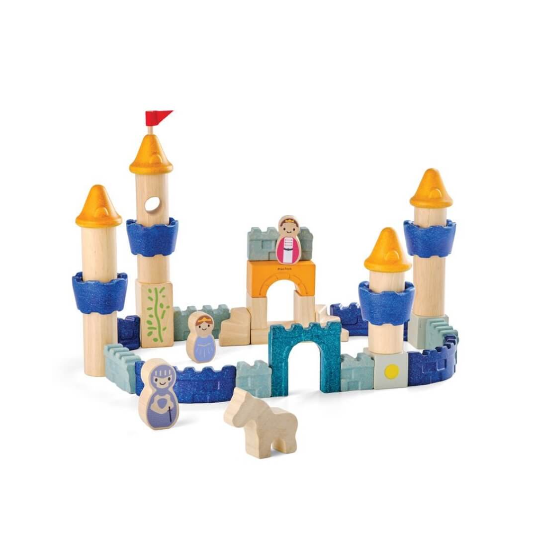 PlanToys wooden castle block set arranged as a fortress with blue and yellow towers, arches, walls, and small wooden figures, including a king, queen, knight, and horse. Bella Luna Toys