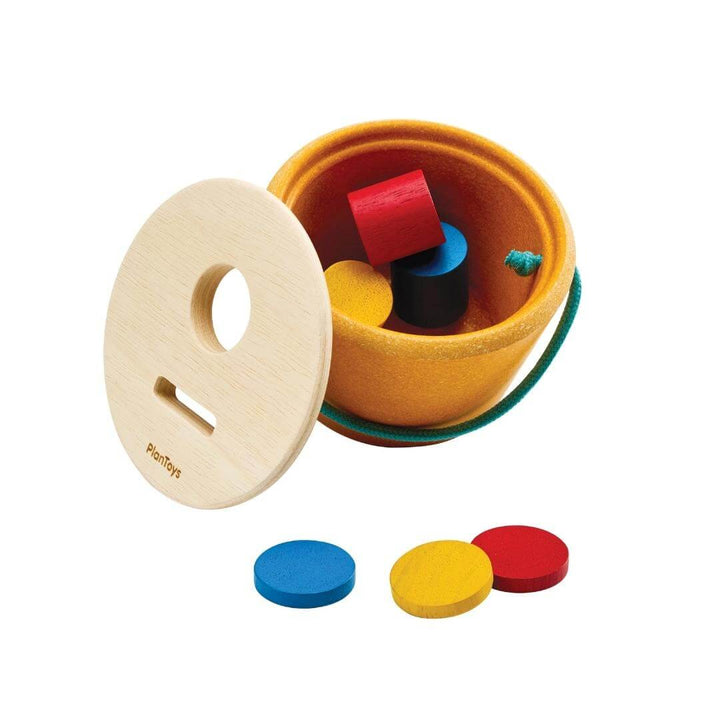 PlanToys Montessori Drop & Fit Bucket with colorful wooden shapes in red, yellow, and blue, designed for shape-sorting and Montessori learning play shown with the top off of the bucket and resting on it's side.