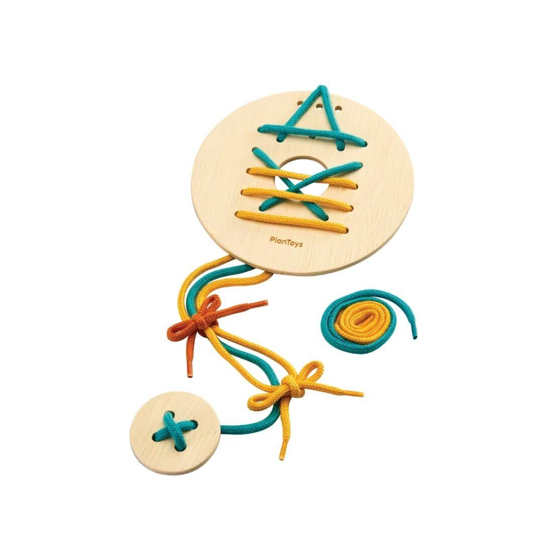 Round wooden lacing board with teal and yellow strings forming shapes, shown with extra laces and a small practice board.