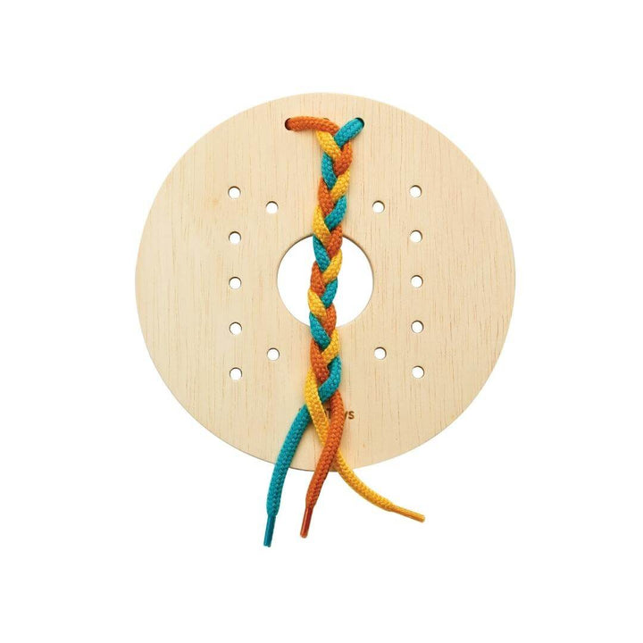 PlanToys round wooden lacing board with yellow, orange, and turquoise string braided.