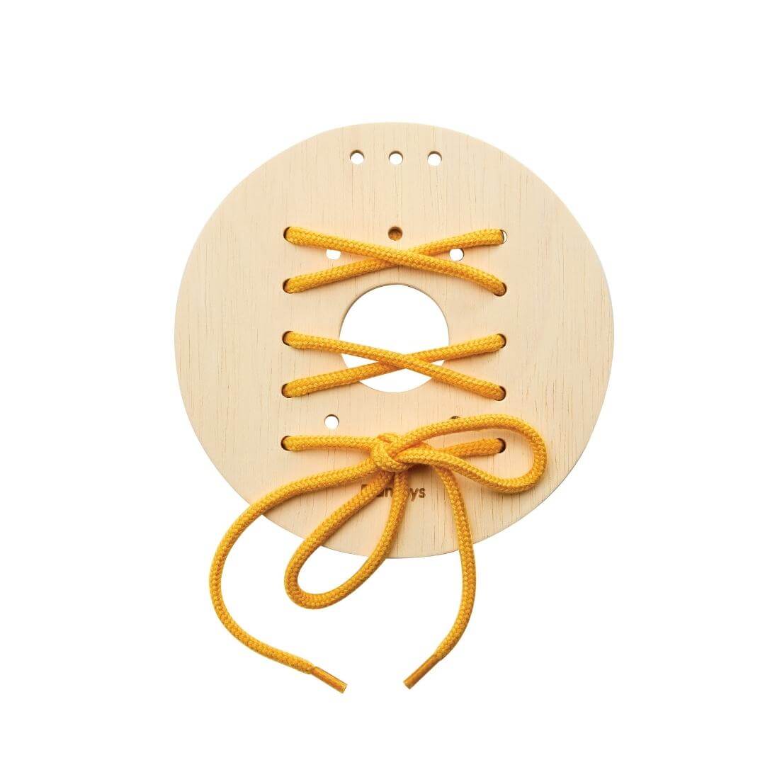 Round wooden lacing board with yellow string threaded in a crisscross pattern and tied in a bow at the bottom.
