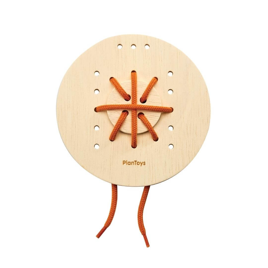 Plan Toys Round wooden lacing board with red string threaded in a crisscross pattern.