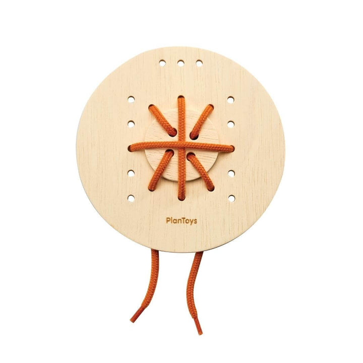 Plan Toys Round wooden lacing board with red string threaded in a crisscross pattern.