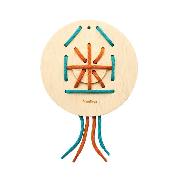 PlanToys round wooden lacing board with turquoise and orange string threaded in an intricate pattern.
