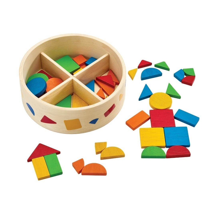 PlanToys Montessori Mosaic Shape Set with round wooden container and colorful geometric tiles arranged into shapes and patterns.