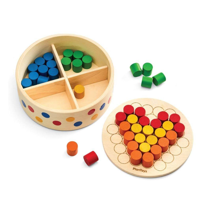 PlanToys Montessori Peg Board Set with round wooden container of colorful pegs and a board showing a heart-shaped peg pattern.