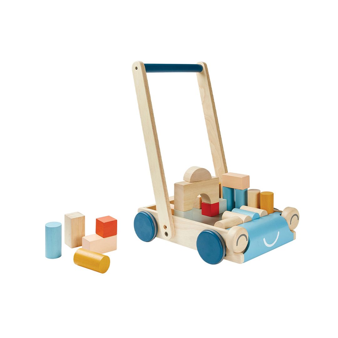 PlanToys Baby Walker Orchard with some of the colorful wooden blocks arranged both inside the walker wagon and on the ground. The walker is designed in natural wood and blue, filled with colorful wooden blocks. A sturdy push toy designed to support early walking and motor skill development.