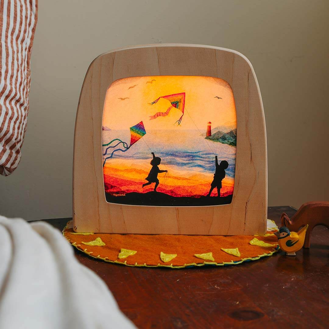 Wooden lamp with a painted design of children flying kites on a beach