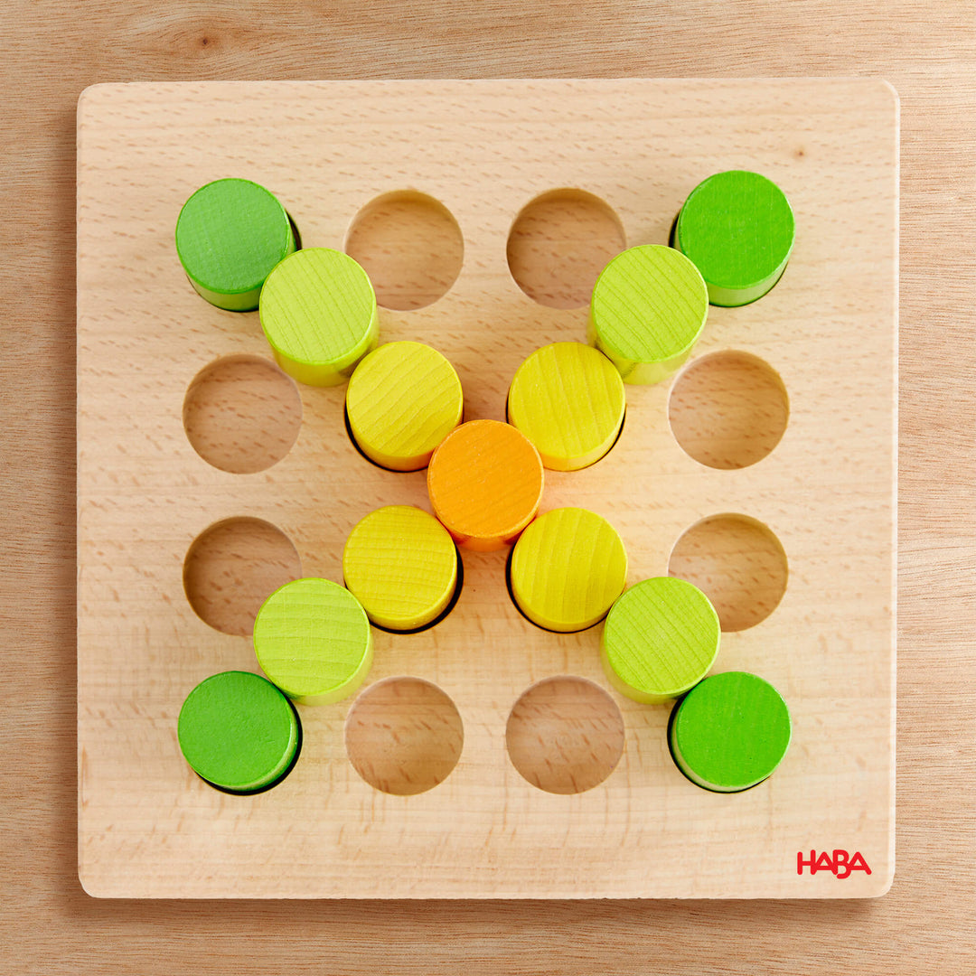 A wooden pegboard with colorful pegs arranged in an X shape.