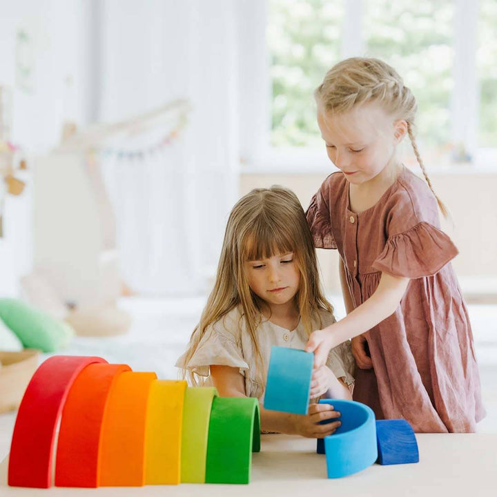Two young girls playing with colorful building blocks indoors.