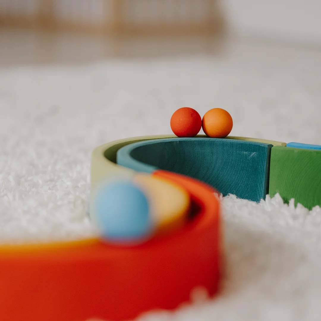 Colorful toy track with two small balls on a textured surface.
