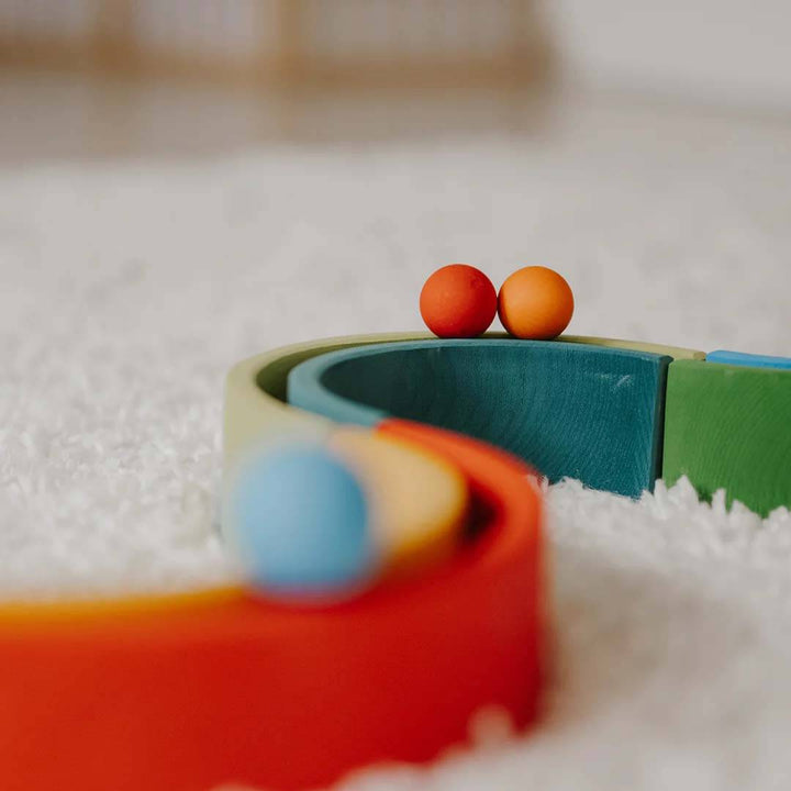 Colorful toy track with two small balls on a textured surface.
