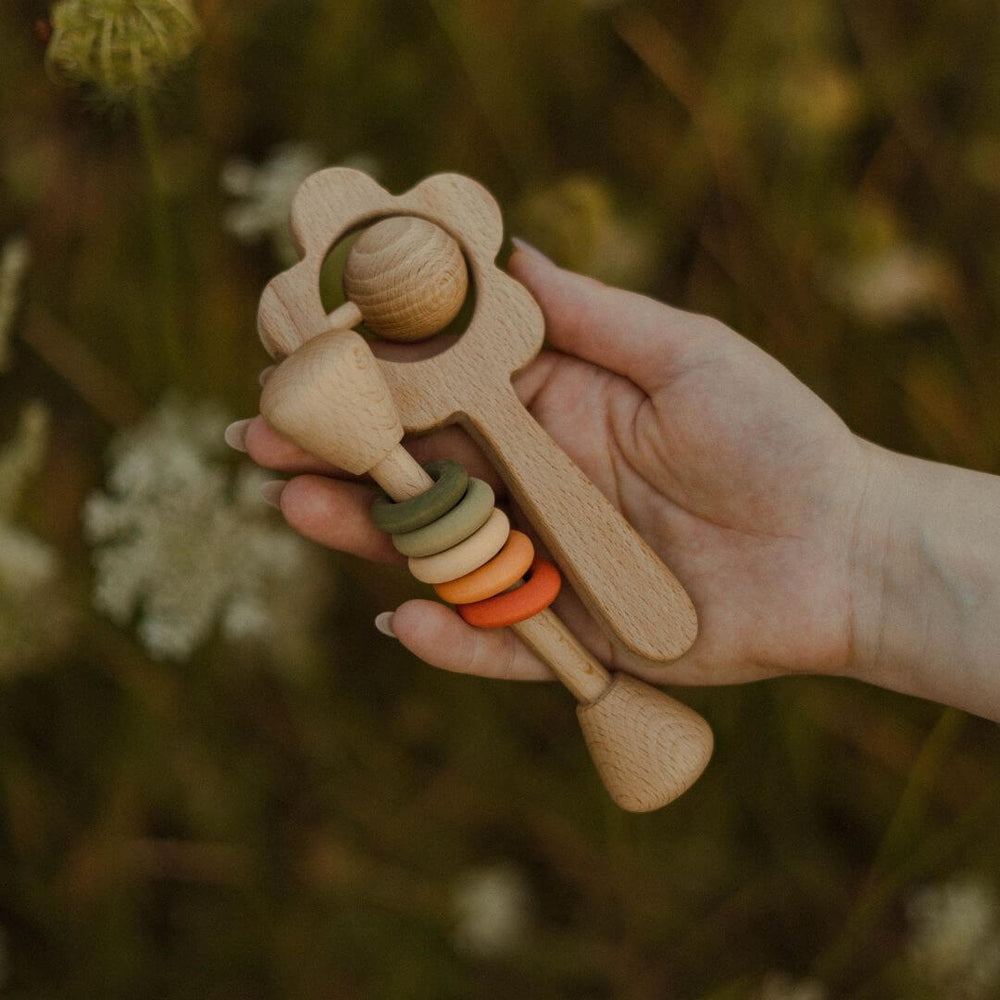 A hand holding two styles of wooden rattles from Sabo.