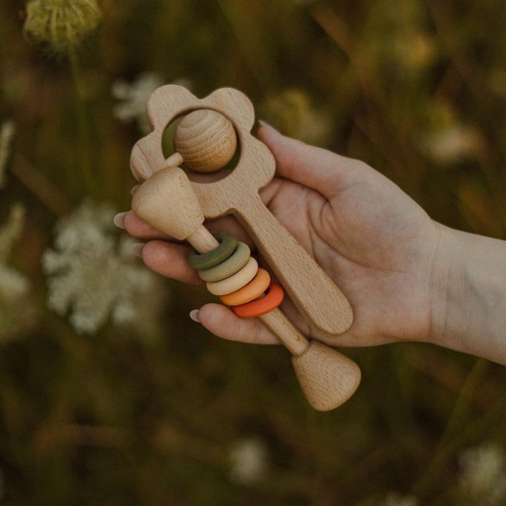 A hand holding two styles of wooden rattles from Sabo.