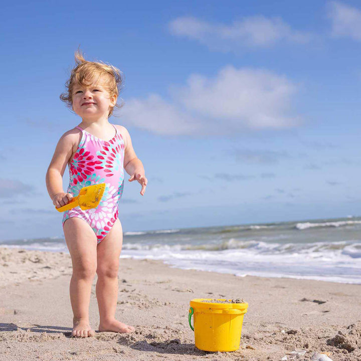 Little girl standing by the ocean holding a yellow Spielstabil Small Sand Scoop with a yellow bucket