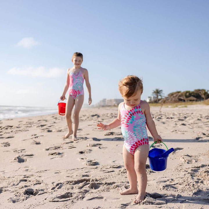 2 girls by the ocean with one holding a blue Spielstabil Pail and blue Small Sand Scoop