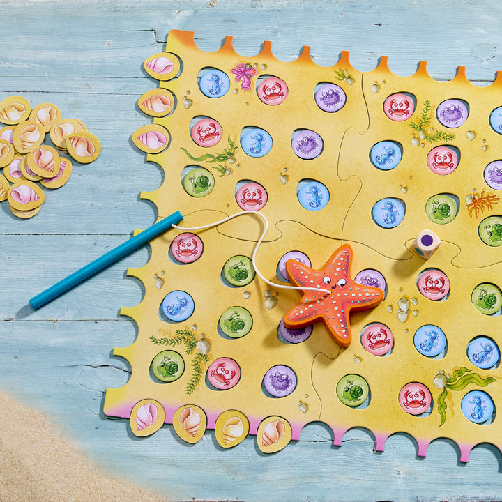Children's fishing game with starfish and colorful pegs on a wooden surface. HABA