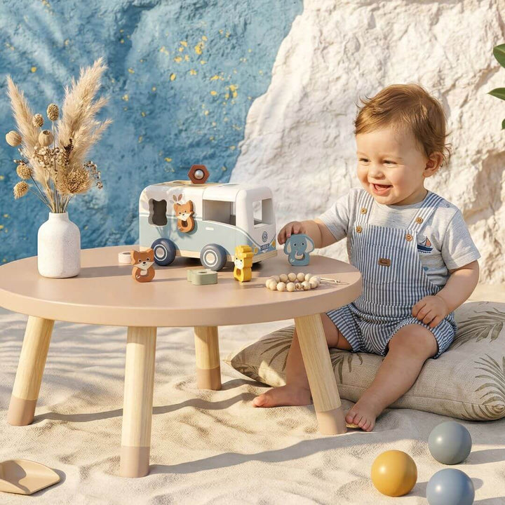 A child playing with animal themed shape sorting van at a small table.