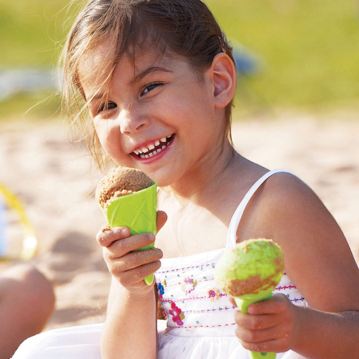 Young girl smiling holding a green Ice Cream Sand Play cone with sand and a green scoop