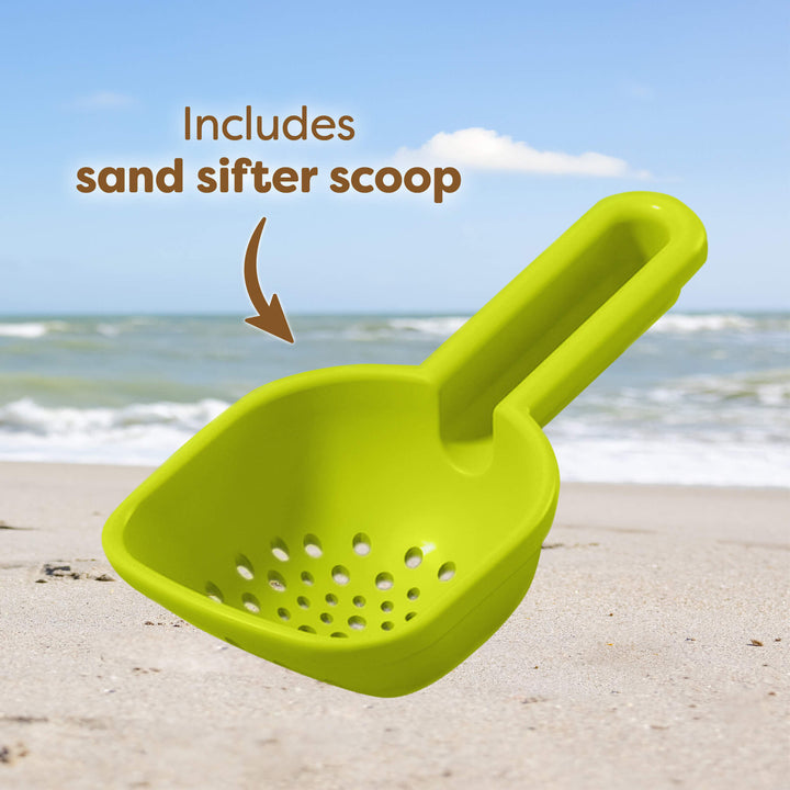 Bright green sand sifter scoop on a beach with the ocean in the background. Text reads "Includes sand sifter scoop."