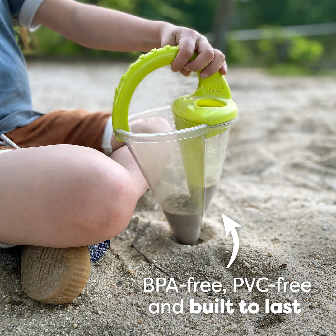Child using a HABA Spilling Funnel with a green handle to dig in the sand. Text reads "BPA-free, PVC-free and built to last."