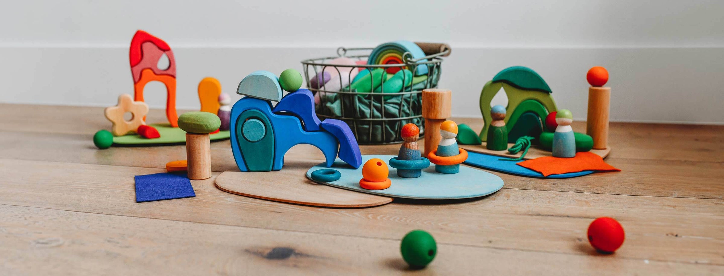Red, blue, and green Grimm's wooden blocks set with green toy basket in the background