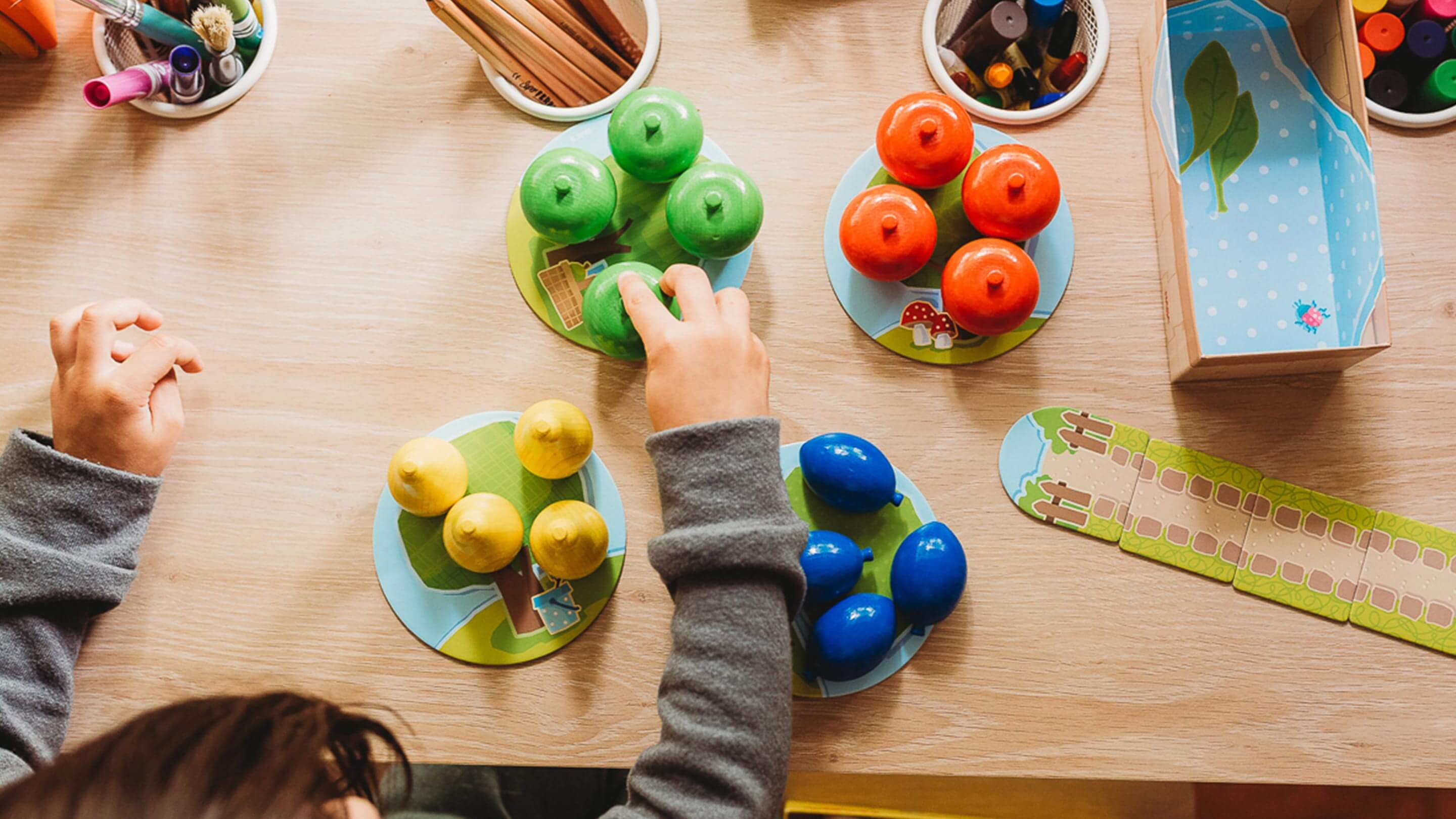 A game is on a wooden table and a child is playing.