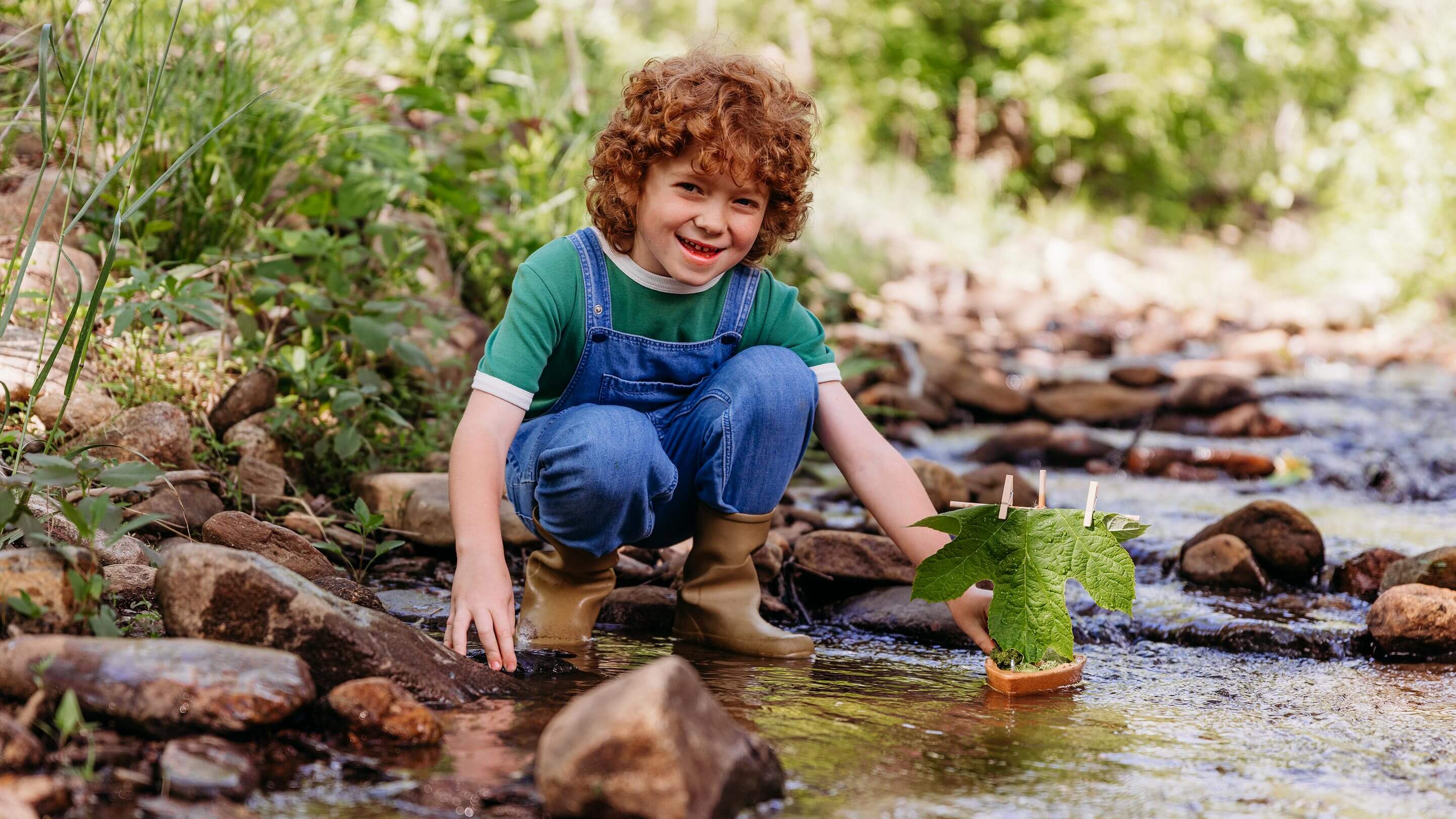 A child is using a cork boat in a stream.
