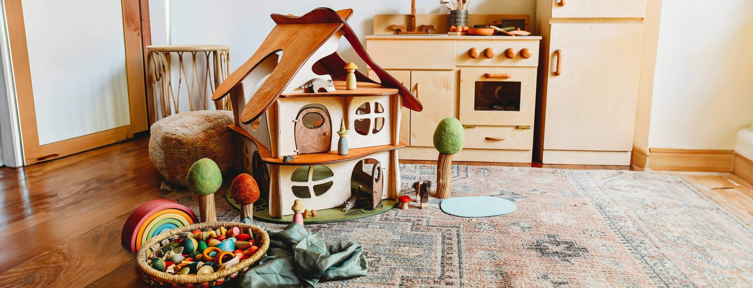 Wooden Dollhouse on rug with felted trees in front of play kitchen and refridgerator