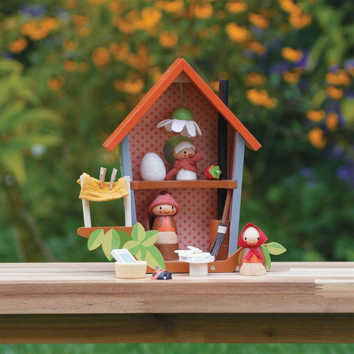 Miniature wooden Tender Leaf Toys bird dollhouse with a bird family on a wooden surface with a blurred natural background