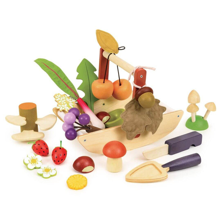 Wooden foraging toy basket with fruits, vegetables, and a boat on a white background. Tender Leaf Toys.