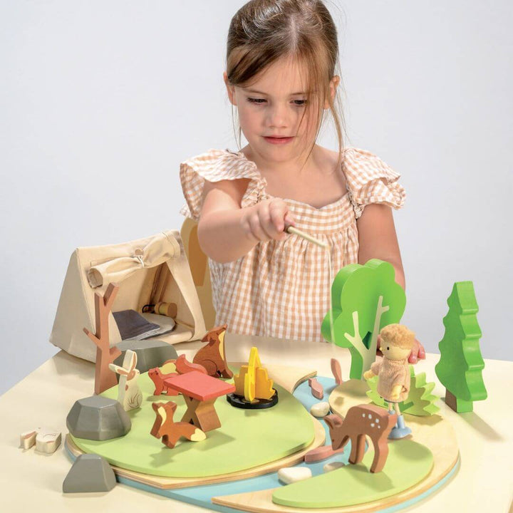 Child playing with a wooden playset featuring animals and a tent. Tender Leaf Toys