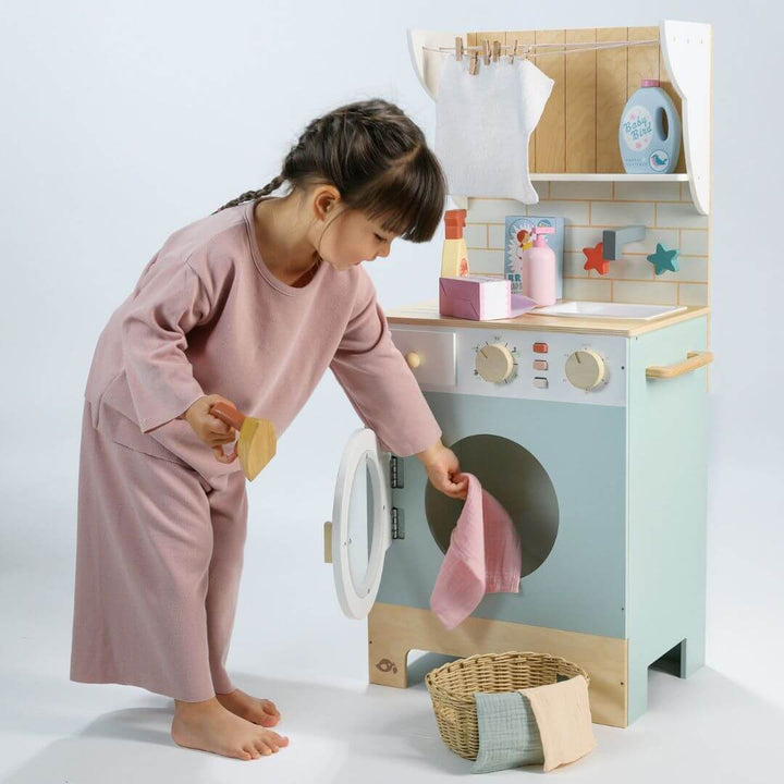 Child playing with a toy washing machine and dryer set on a white background.