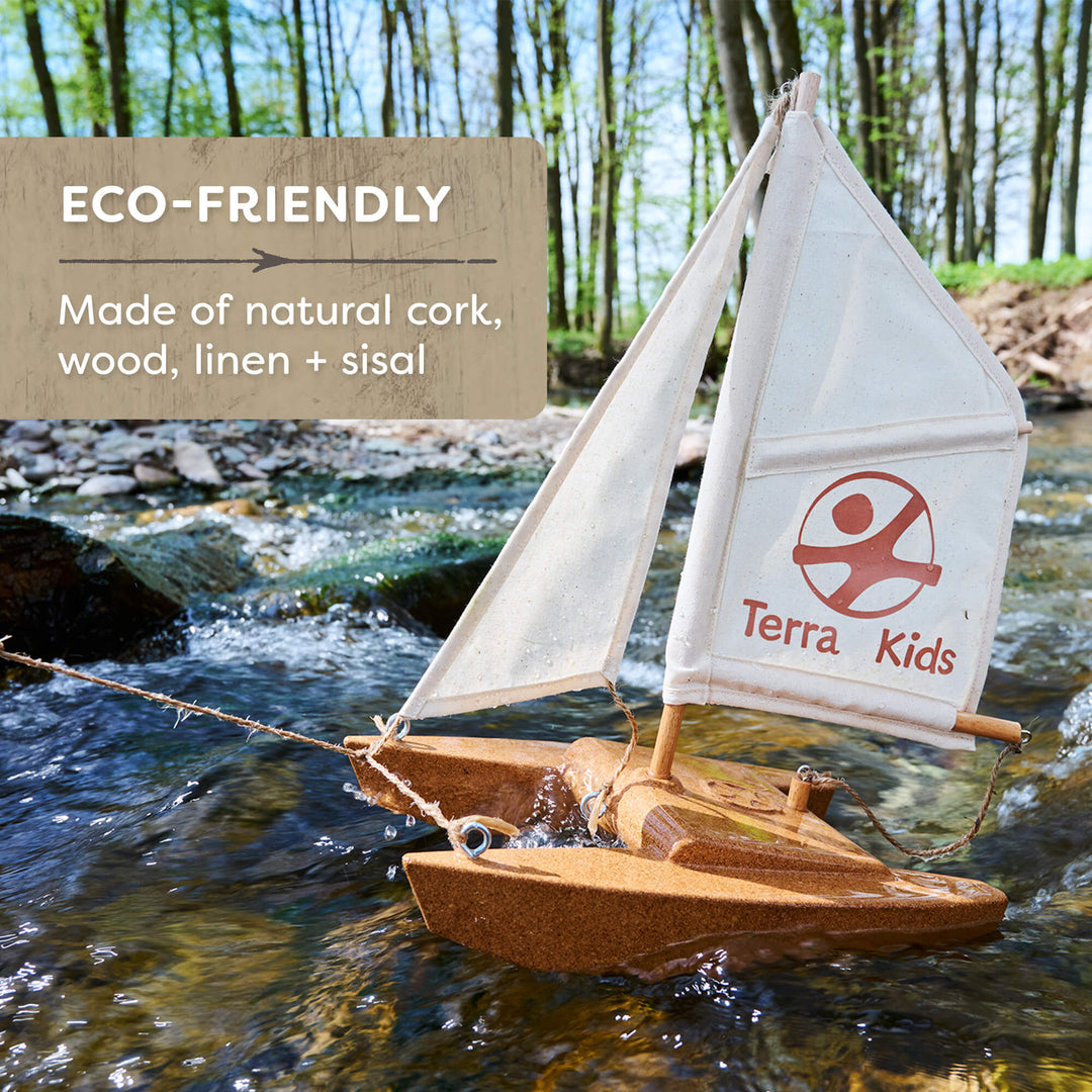 Eco-friendly toy sailboat with cork, wood, linen, and sisal materials, branded 'Terra Kids', on a natural setting.