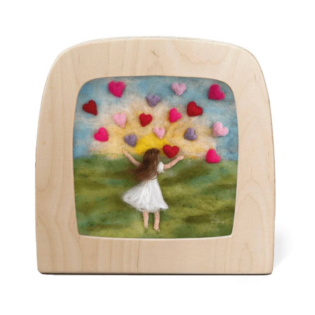 Toverlux lamp with a wool felted scene of a girl holding up her arms with red, pink and purple hearts flying above her.